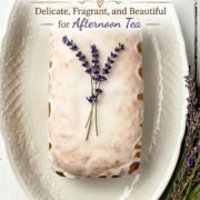 Iced lavender tea bread garnished with sprigs of lavender on a white platter, with a bundle of lavender tied with ribbon beside it. Perfect for afternoon tea, this lavender tea bread adds a fragrant touch to your gathering.