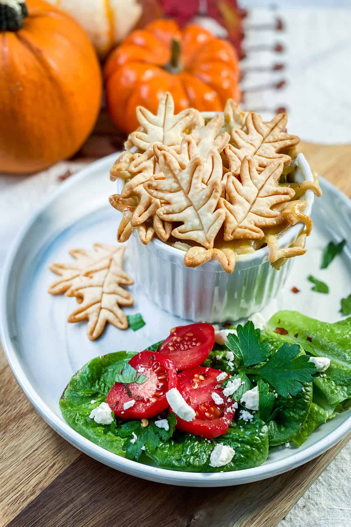 Individual mini chicken pot pie with pastry fall leaf shapes in a ramekin ready for serving with a salad.