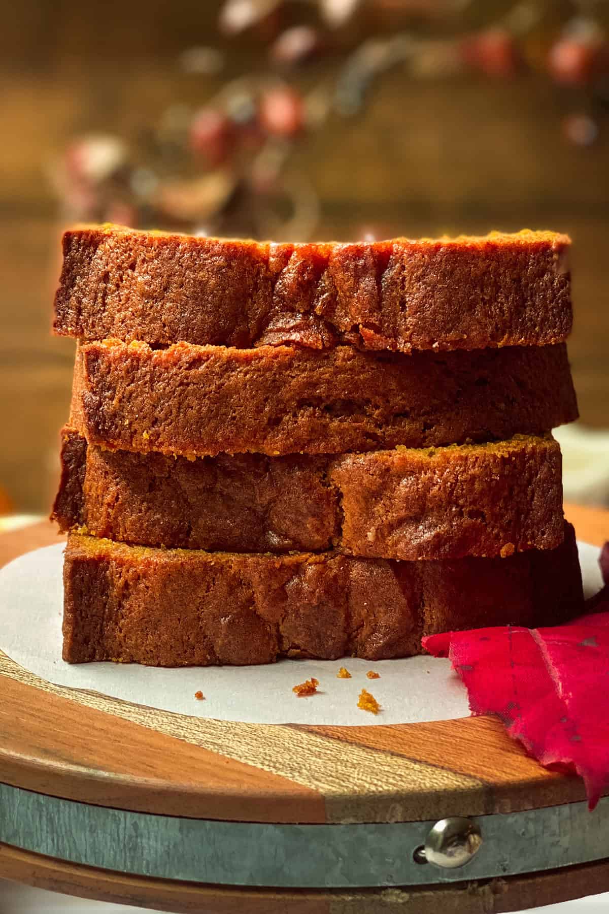 Stacked slices of homemade pumpkin bread on a rustic wooden board, ready to serve.