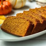 Square image of sliced pumpkin bread on a platter, a cozy fall baking recipe.