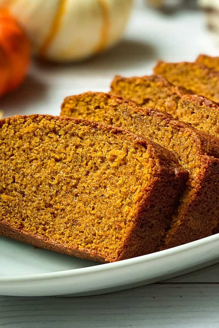 Square image of sliced pumpkin bread on a platter, a cozy fall baking recipe.