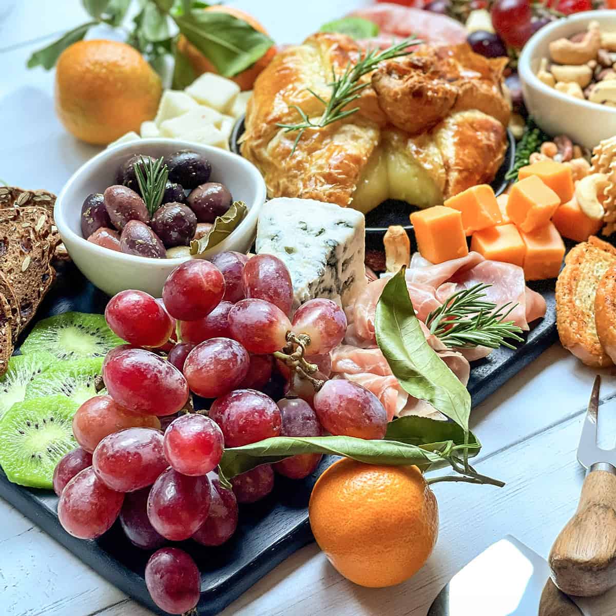Closeup view of fall fruits, cheese, nuts, olives, spreads, and more for an easy fall charcuterie board.