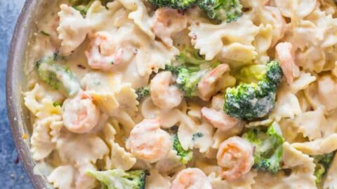 A skillet filled with creamy pasta, shrimp, and broccoli mixed in a white sauce, viewed from above on a blue surface—perfect for Healthy Comfort Food Dinners.
