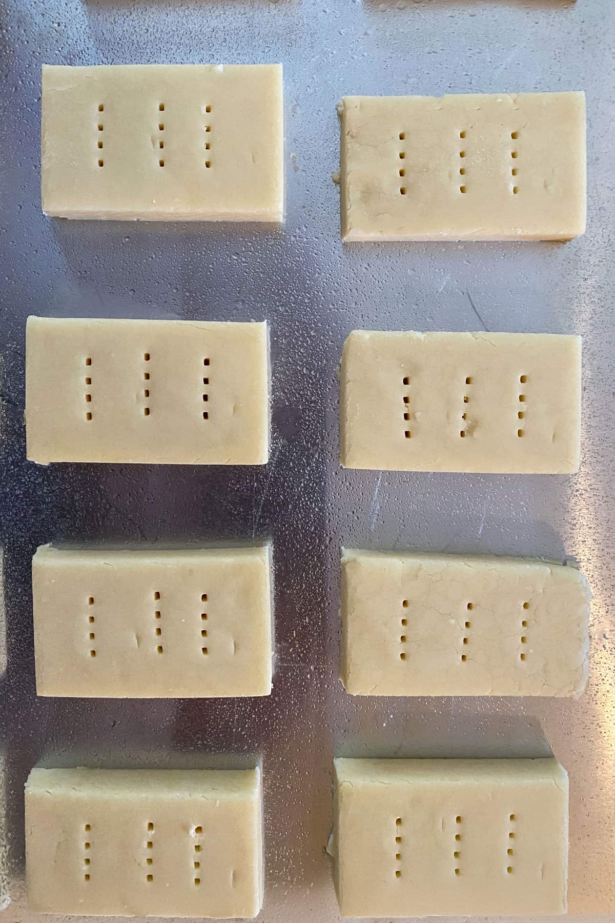 Unbaked shortbread finger cookies, pricked with fork tines, and ready for the oven.