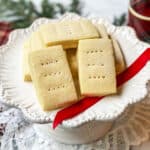 Close-up of Buckingham Palace shortbread cookies stacked on a white pedestal plate with sanding sugar and fork marks.