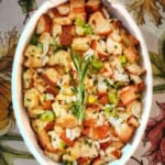 Top view of classic stuffing recipe in an oval ceramic baking dish and garnished with a rosemary sprig.