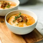 Bowl of creamy root vegetable soup in a bowl and garnished with toasted croutons and fresh thyme.