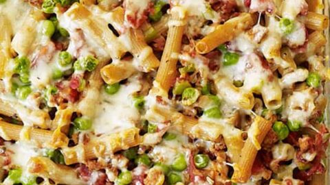 A cozy country dinner favorite, this baked pasta casserole features melted cheese, green peas, ground meat, and tomato sauce in a glass dish.