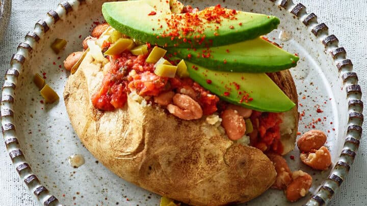 Baked potato topped with pinto beans, salsa, sliced avocado, red chili flakes, and diced jalapeños on a speckled ceramic plate—one of our Healthy 5 Ingredient Dinners.