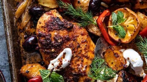 A perfect March sheet pan dinner: roasted chicken breasts, potatoes, olives, red peppers, fresh dill, mint, feta cubes, lemon slices, and dollops of yogurt for a flavorful one-pan meal.