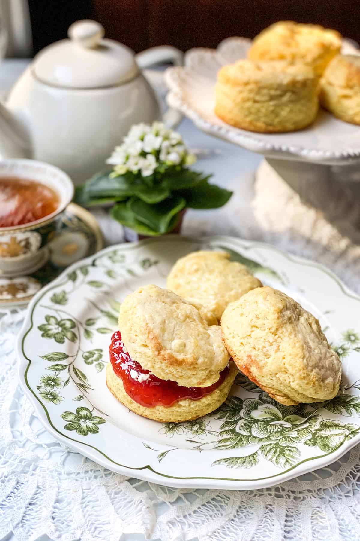 A plate with three scones, made from an authentic Irish scones recipe and one filled with strawberry jam and clotted cream.