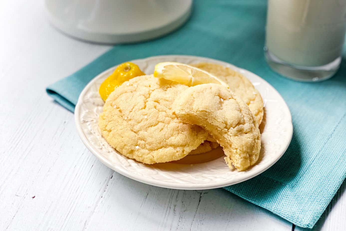 3 Homemade Lemon Sugar Cookies on a White Plate with a Bite Missing