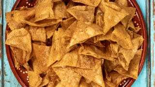 Top view of homemade tortilla chips in a terra cotta bowl.