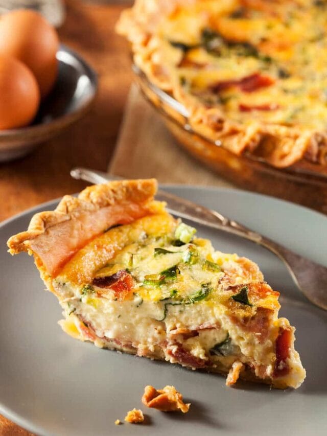 Side view of a slice of Bacon, Cheese, and Spinach Quiche on a grey plate