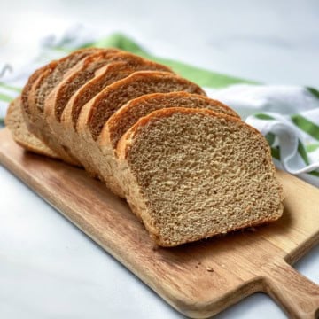 Sliced whole wheat bread made in two loaves with a striped linen in the background.