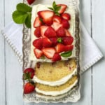 Rectangular strawberry cake with white frosting, topped with fresh strawberries and mint.