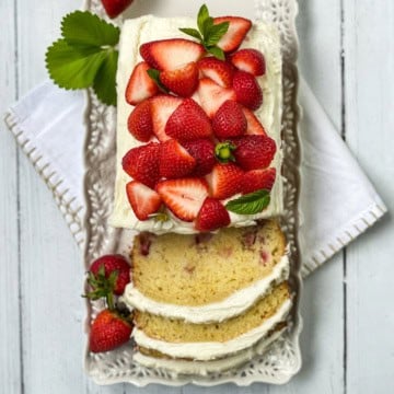 Rectangular strawberry cake with white frosting, topped with fresh strawberries and mint.