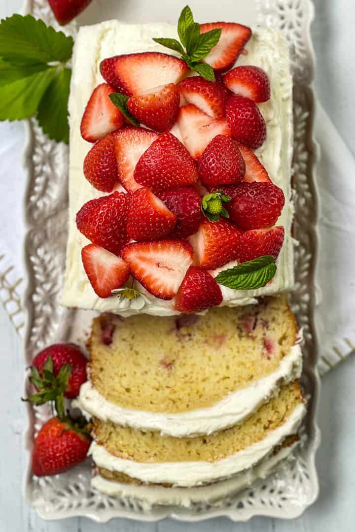 Rectangular strawberry cake with white frosting, topped with fresh strawberries and mint.