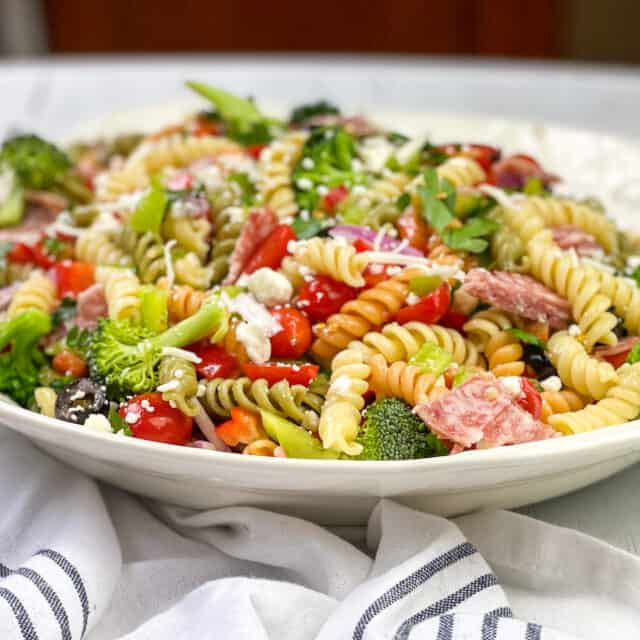 Pasta Salad in a White Bowl with salami and vegetables.