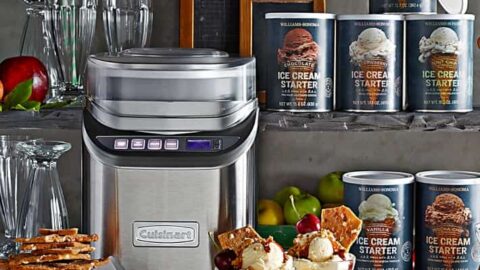 A stainless steel Cuisinart ice cream maker sits on a counter with ice cream starter cans, apple pie brittle, sundae glasses, and two ice cream sundaes—an ideal setup for creative Father’s Day gifts.