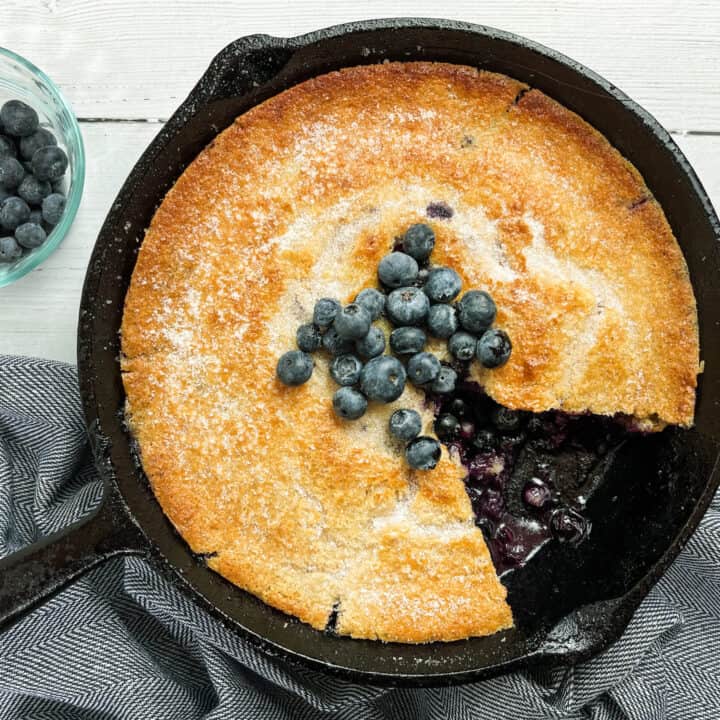 Blueberry Cobbler in a cast iron skillet with slice missing