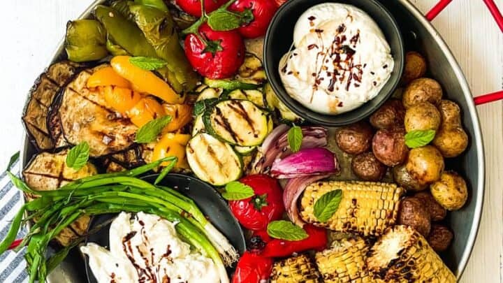 Top view of Grilled Vegetables Platter with bowls of burrato cheese on a white background.