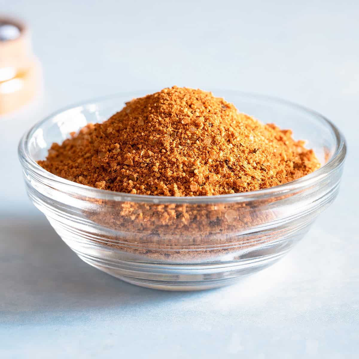 A small glass bowl filled with a dry rub recipe for grilling in a glass container.