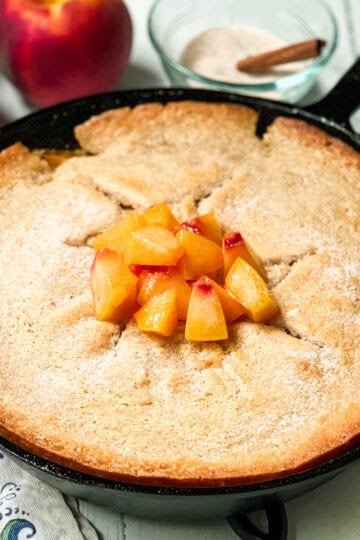 Just baked skillet peach cobbler in a cast iron skillet with a garnish of chopped peaches.
