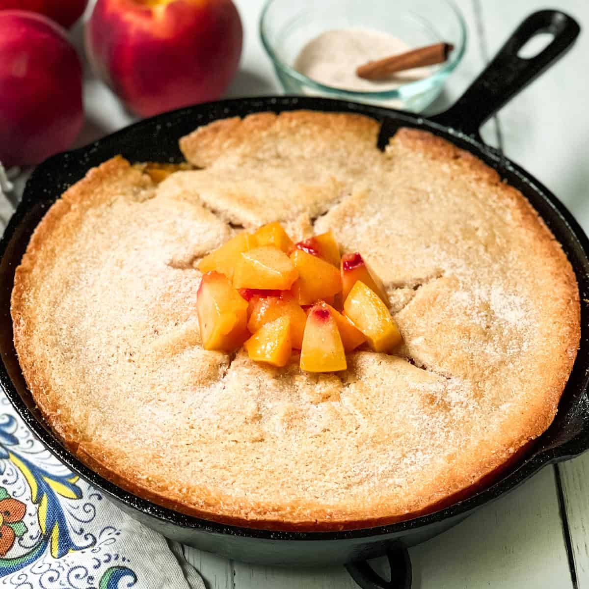 Just baked skillet peach cobbler in a cast iron skillet with a garnish of chopped peaches.