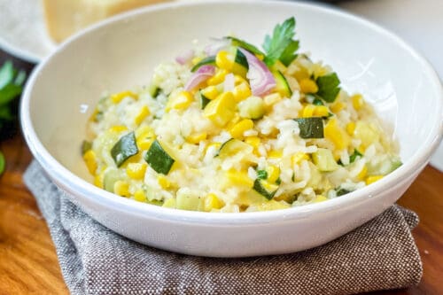 Bowl of Instant Pot Risotto with Zucchini and Corn with a Pressure Cooker in the background