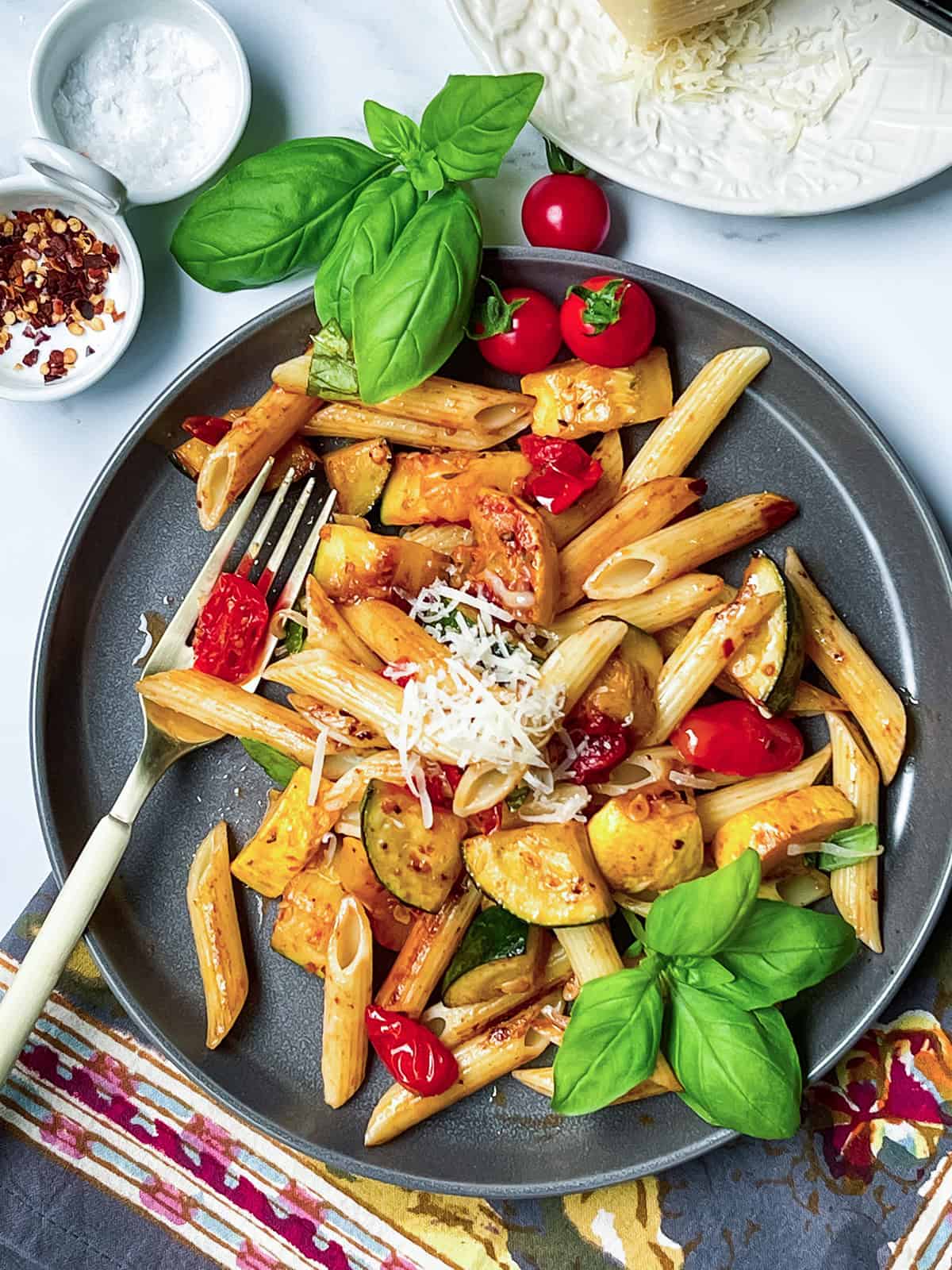 Zucchini pasta on a serving plate with fresh grated parmesan and a fork.