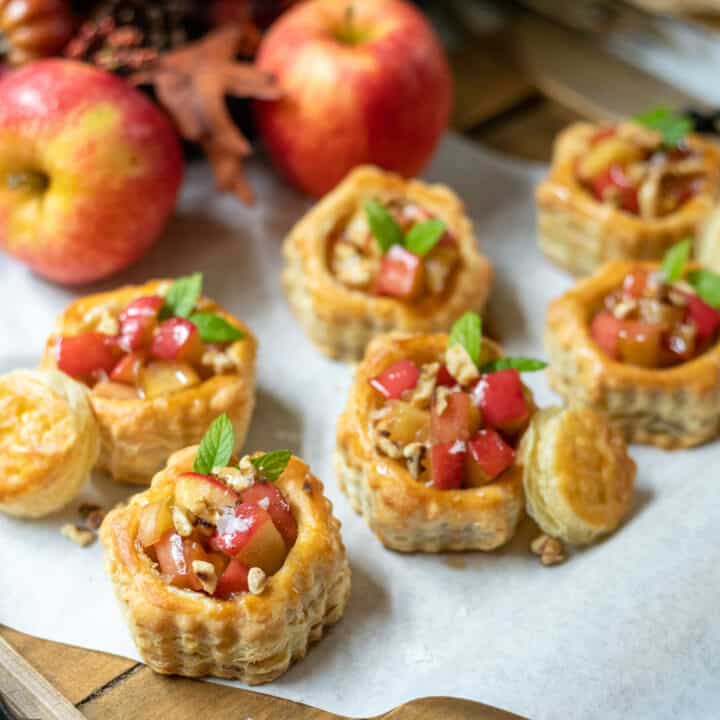Side view of mini apple tarts on a wood board.