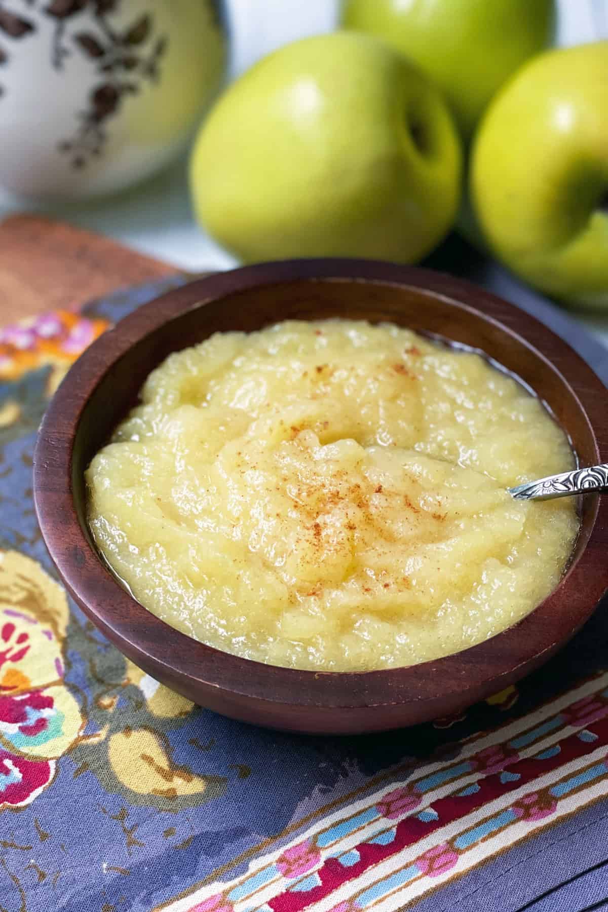 Homemade applesauce in a wooden bowl with a spoon.