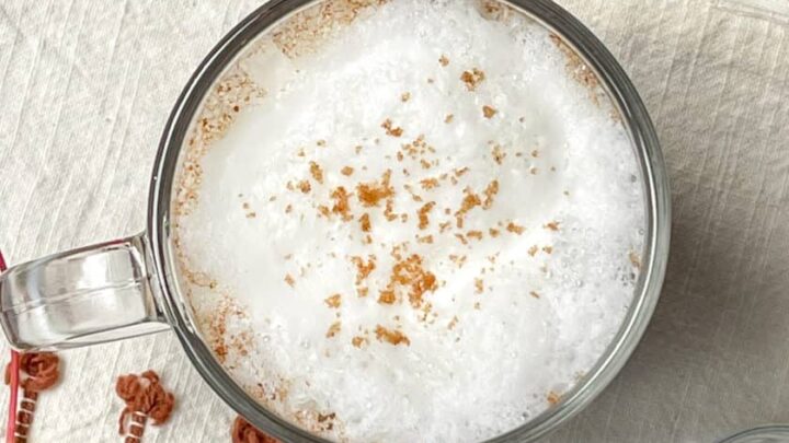 Top down image of frothed milk on top of a Maple Cinnamon Latte sprinkled with ground cinnamon.