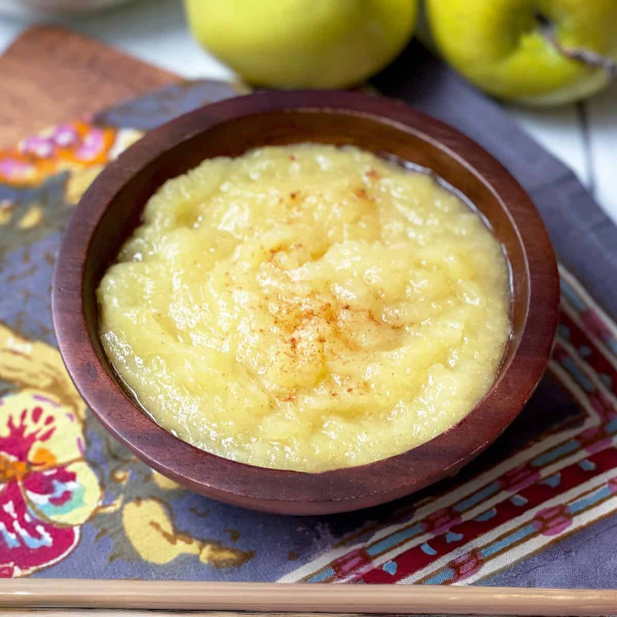 Serving of freshly made applesauce in a wooden bowl and sprinkled with cinnamon