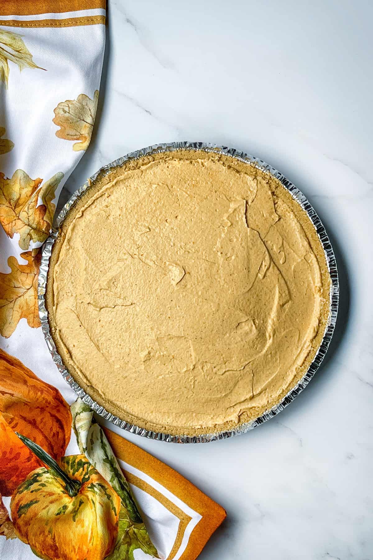 Pumpkin cheesecake filling spread evenly into graham cracker crust before chilling.