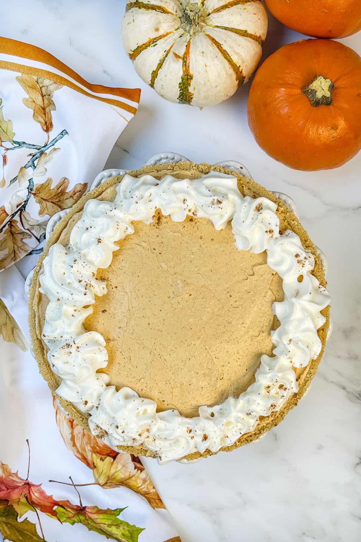 No bake pumpkin cheesecake topped with whipped cream swirls and ready to chill