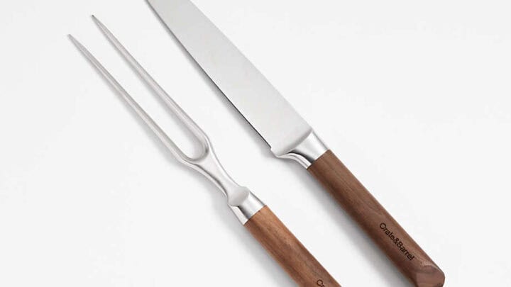 A carving knife and fork set with wooden handles and stainless steel blades, placed side by side on a white surface—Thanksgiving kitchen essential tools for your holiday feast.