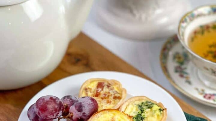 Side view of 3 mini quiche with a teacup and teapot