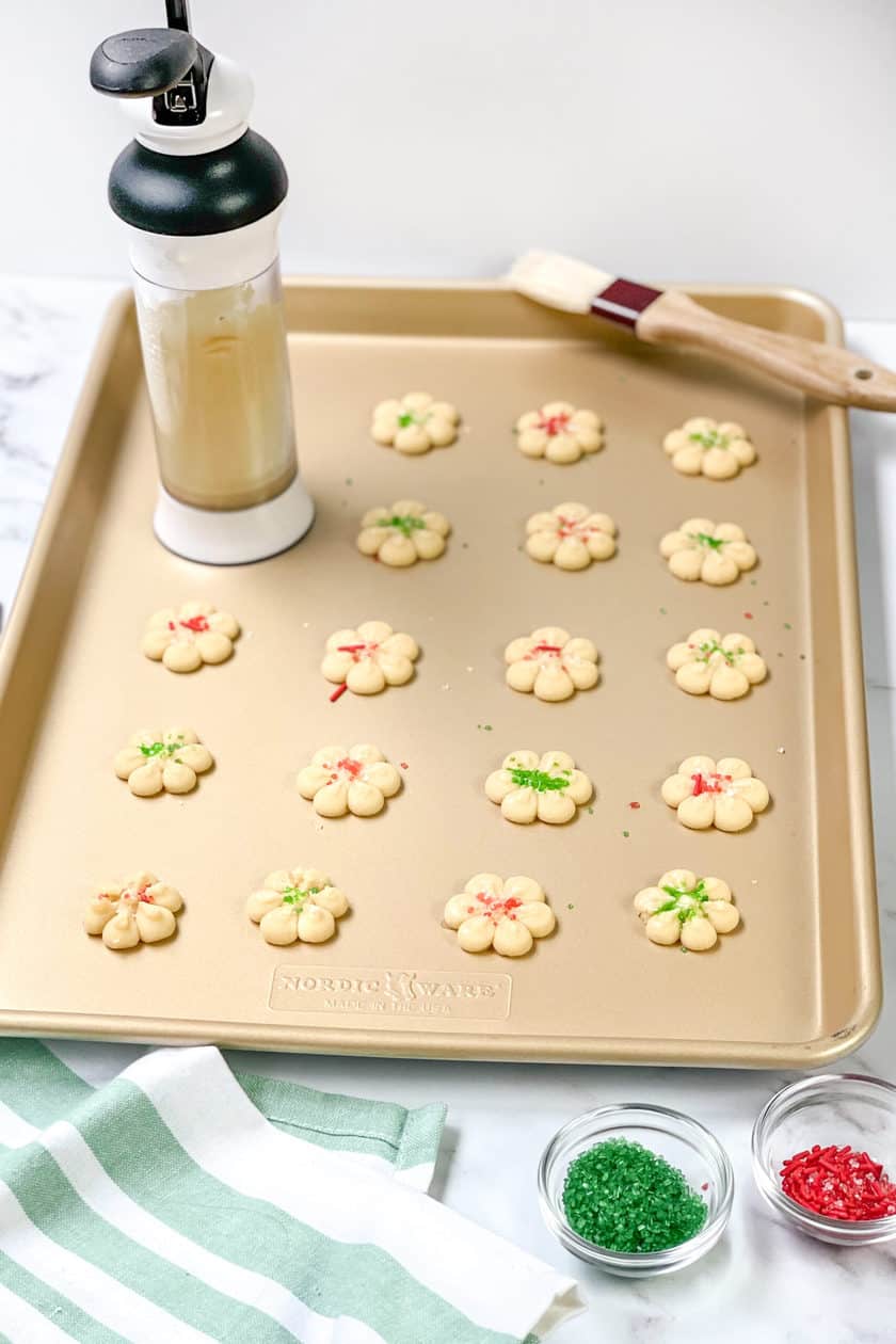 Unbaked Spritz Cookies on baking sheet with cookie press