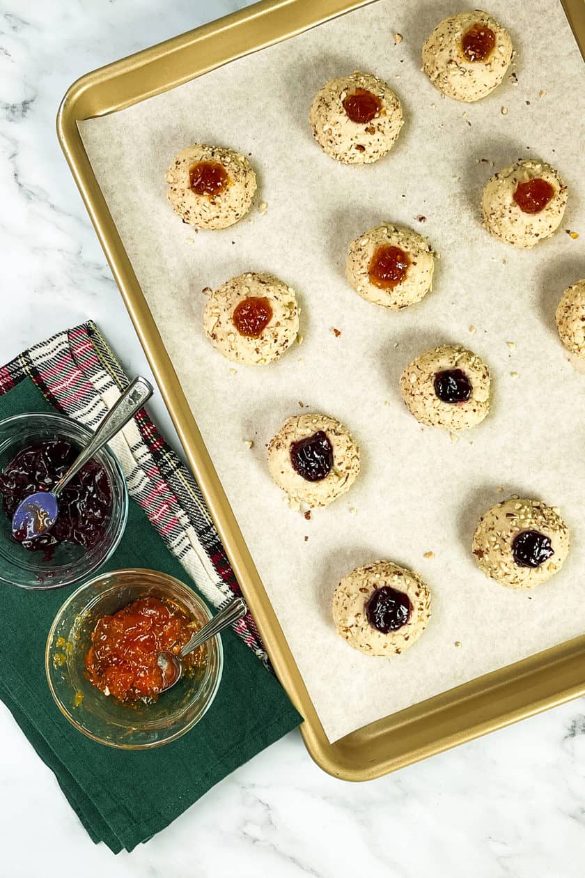 Filling warm just baked thumbprint cookies with jam