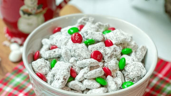 Bowl of Christmas Muddy Buddies with Hot Chocolate in the Background