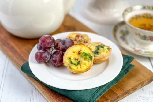Closeup view of 3 mini quiche on a plate with grapes