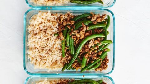 Three glass meal prep containers filled with brown rice and a stir-fry of ground meat and green snap peas, arranged vertically—perfect for healthy 4 ingredient dinners.
