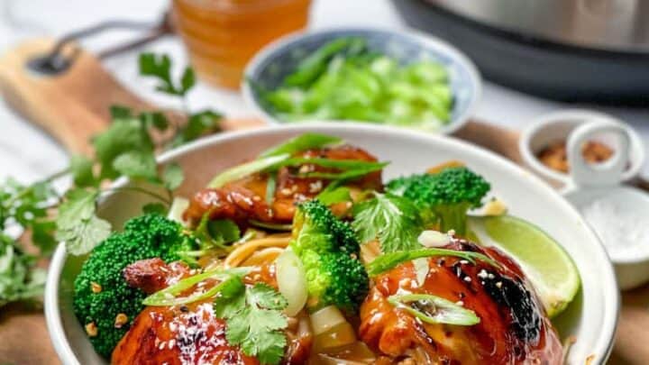 Distant view of Instant Pot Asian BBQ Chicken Thighs with a pressure cooker in the background
