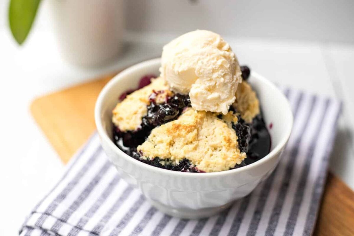 Dish of blueberry cobbler topped with vanilla ice cream