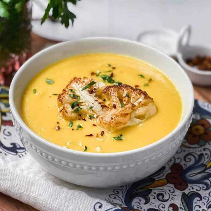 Bowl of Creamy Cauliflower Soup with Turmeric and Cumin with chopped parsley as garnish