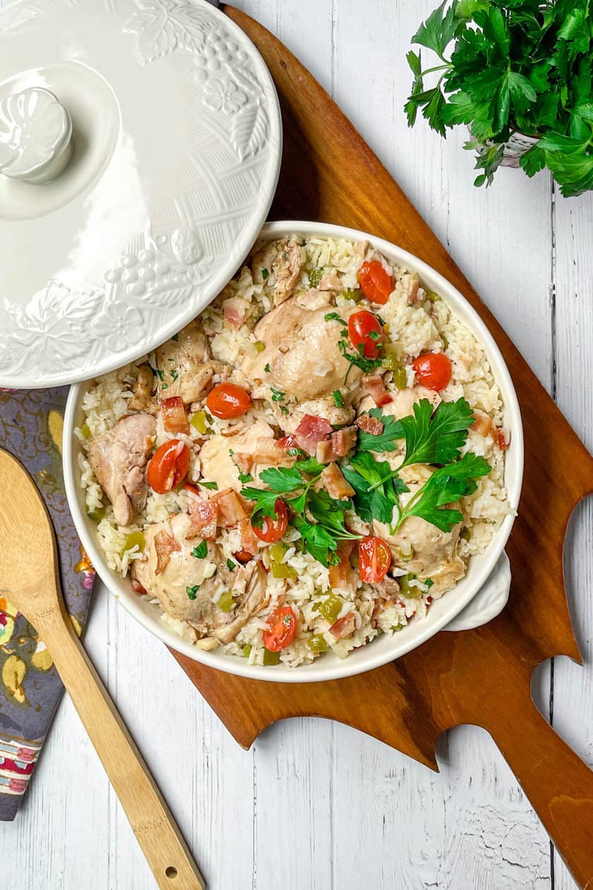 Top view of Chicken Perloo with fresh tomatoes and parsley in a covered casserole dish