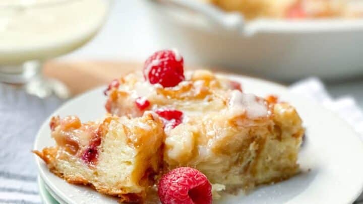 Serving of Croissant Bread Pudding with fresh raspberries and warm Vanilla Sauce.