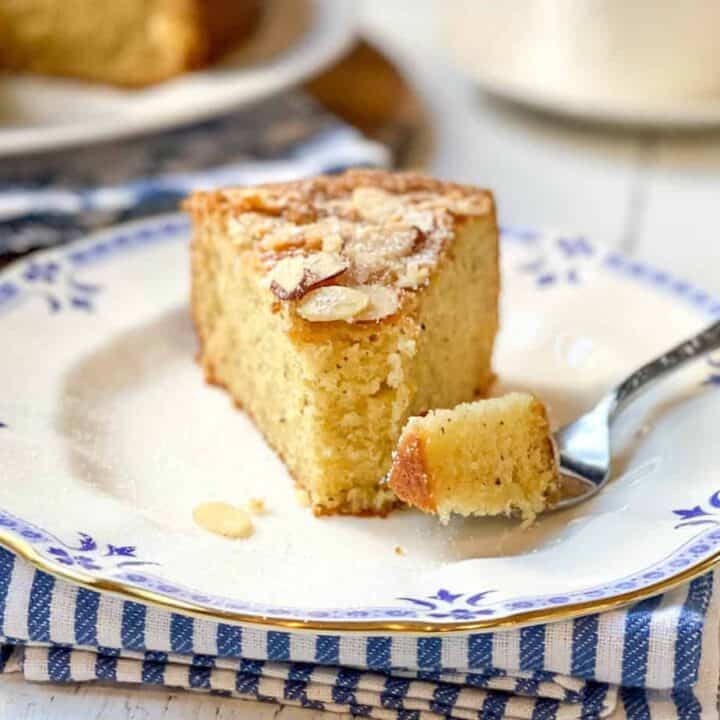 Slice of Almond Cake with a bite missing on a blue and white plate